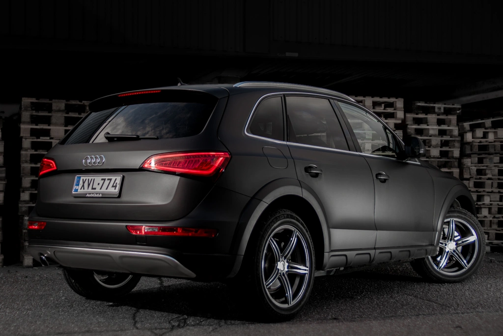 Musta citymaasturi jossa punaiset takavalot ja taustalla näkyy pakkauslavoja. vuoksen media ajoneuvokuvaus.