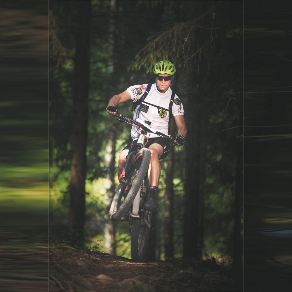 Maastopyöräilijä ajaa metsässä keulimalla.