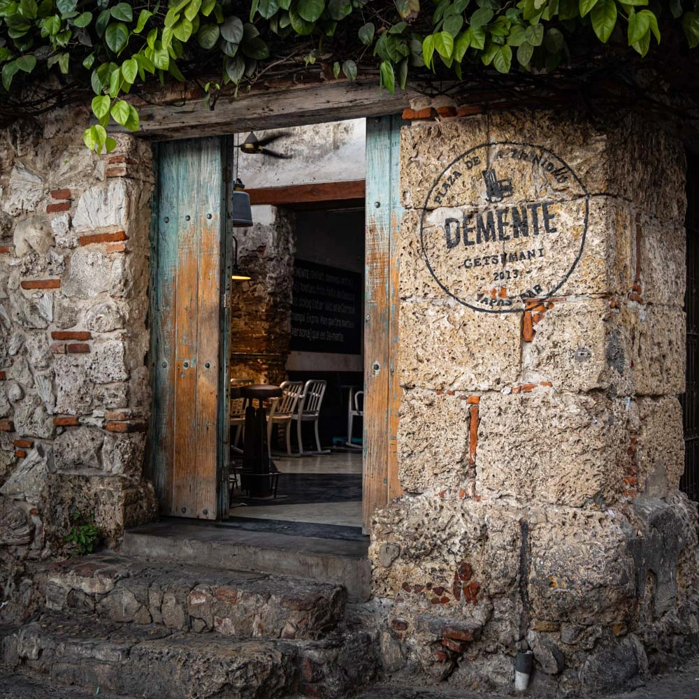 Vanhan kiviseinäisen ravintolan sisäänkäynti ja ravintolan ovi on auki, josta näkyy sisälle ravintolaan.