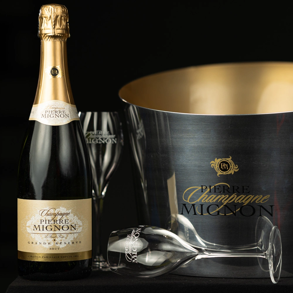 Shampanjapullo ja kaksi tyhjää shampanjalasia, joista toinen kyljellään ja yksi cooler-astia